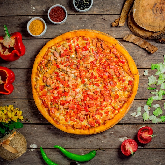 Bovenaanzicht van pizza met gehakte groenten, champignons en worstjes