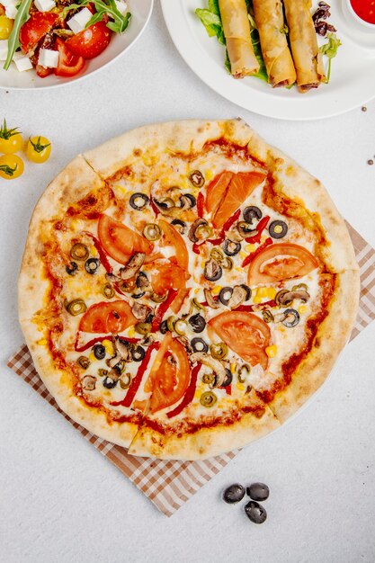 Bovenaanzicht van pizza met tomaten, champignons en olijven
