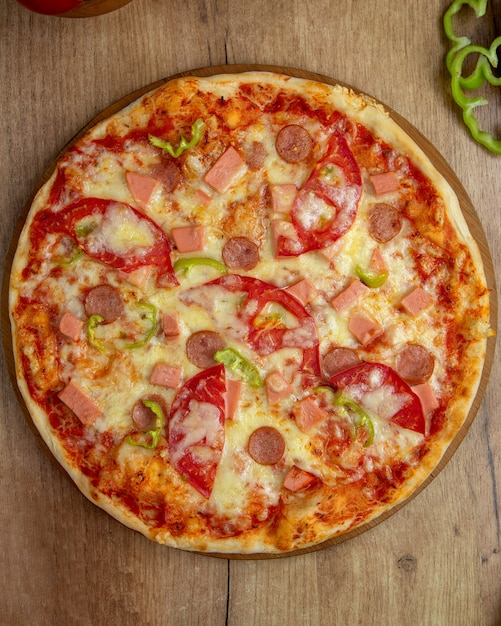 Bovenaanzicht van pizza met worst, tomaat, paprika en kaas