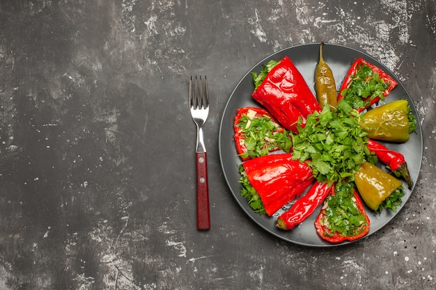 Bovenaanzicht van plaat van paprika kleurrijke paprika's met kruiden op de plaat tussen mes en vork