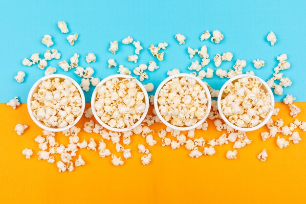 Bovenaanzicht van popcorn in kommen op blauwe en gele horizontaal