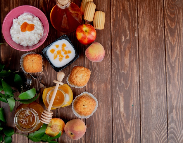 Bovenaanzicht van potten jam als perzik en pruim met cupcakes perziken kwark op hout versierd met bladeren met kopie ruimte