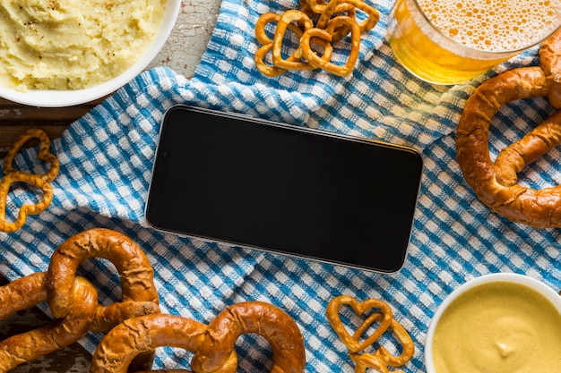 Bovenaanzicht van pretzels met bier en smartphone