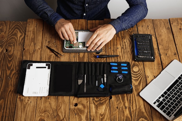 Bovenaanzicht van professionele schone elektronische apparaat op houten tafel in zijn lab in de buurt van zijn tools voordat ze worden gedemonteerd