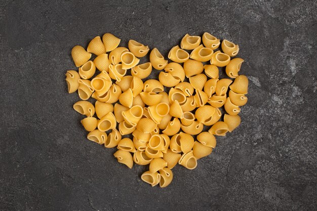 Bovenaanzicht van rauwe Italiaanse pasta die hartvorm op het donkere oppervlak vormt