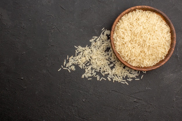 Gratis foto bovenaanzicht van rauwe rijst in bruine plaat op donkergrijs oppervlak