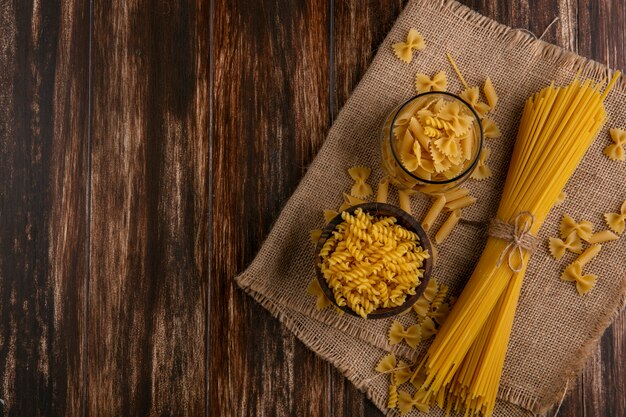 Bovenaanzicht van rauwe spaghetti met rauwe pasta op een beige servet op een houten oppervlak