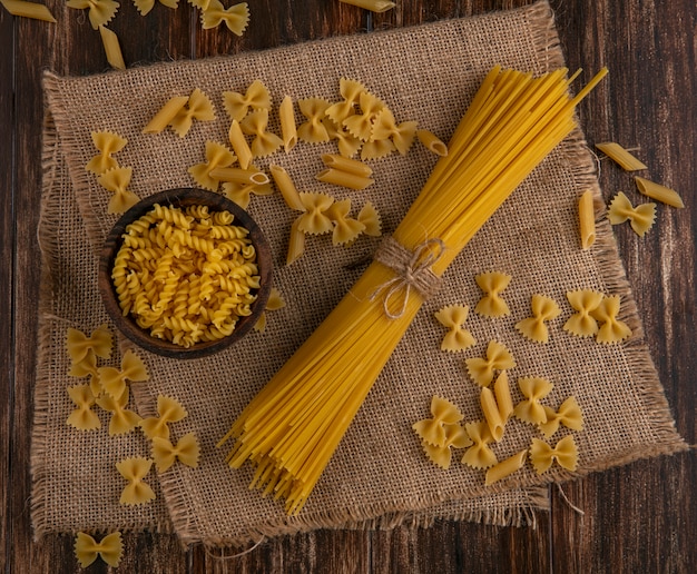 Bovenaanzicht van rauwe spaghetti met rauwe pasta op een beige servet