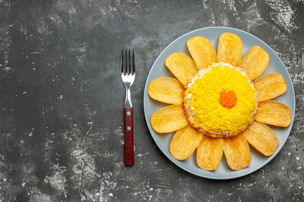 Bovenaanzicht van rechts van salade met chips rond op plaat op donkergrijze achtergrond