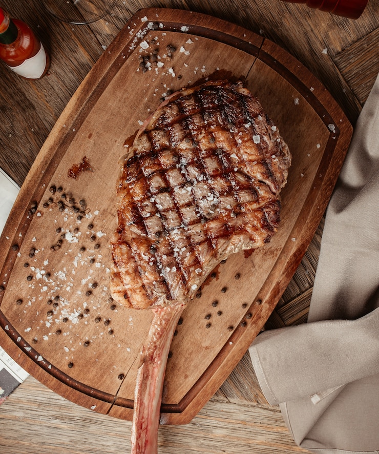 Gratis Foto bovenaanzicht van ribeye steak geserveerd op een houten bord