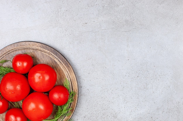Bovenaanzicht van rijpe rode tomaten in houten bord.