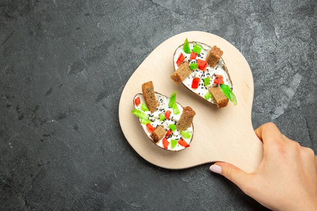 Bovenaanzicht van romige avocado's met gesneden paprika en stukjes brood op grijze ondergrond