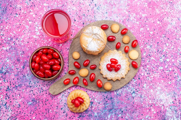 Bovenaanzicht van romige sandwichkoekjes met kornoeljessap van rode kornoeljes op heldere, koekjescake biscuit zoetzure fruitbes