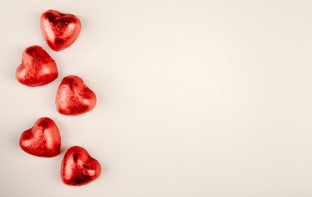 Gratis foto bovenaanzicht van rood hartvormige snoepjes geïsoleerd op een witte tafel met kopie ruimte