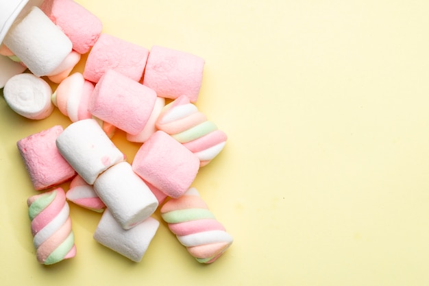 Bovenaanzicht van roze en witte marshmallow verspreid op geel