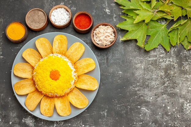 Bovenaanzicht van salade aan de linkerkant met kruiden aan de kant met bladeren aan de rechterkant op donkergrijze tafel