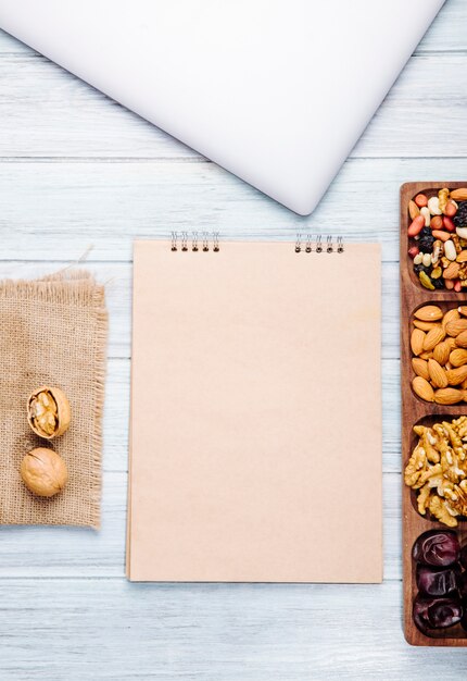 Bovenaanzicht van schetsboek en noten mix met walnoten amandel en zoete gedroogde dadels op houten tafel