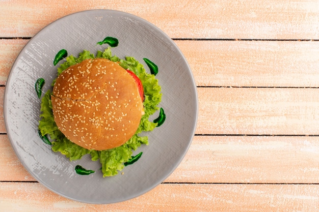 Bovenaanzicht van smakelijke broodje kip met groene salade en groenten in plaat op het houten rustieke crème oppervlak