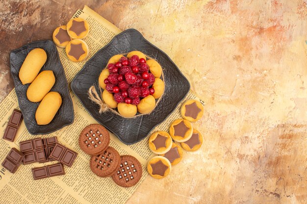 Bovenaanzicht van smakelijke cake verschillende koekjes op bruine plaat op gemengde kleurentafel