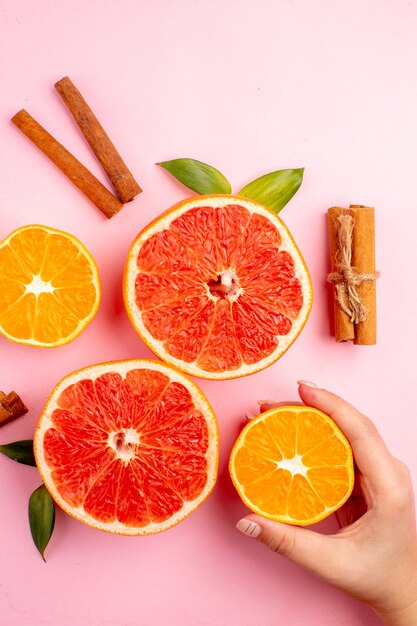 Bovenaanzicht van smakelijke grapefruits fruit plakjes met kaneel op het roze oppervlak