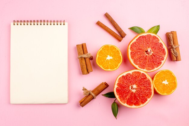 Bovenaanzicht van smakelijke grapefruits fruit plakjes met kaneel op het roze oppervlak