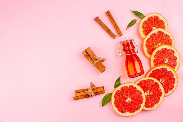 Bovenaanzicht van smakelijke grapefruits met kaneel op roze oppervlak