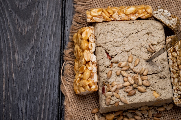 Bovenaanzicht van smakelijke halva met honingrepen met pinda's en zonnebloempitten op zak