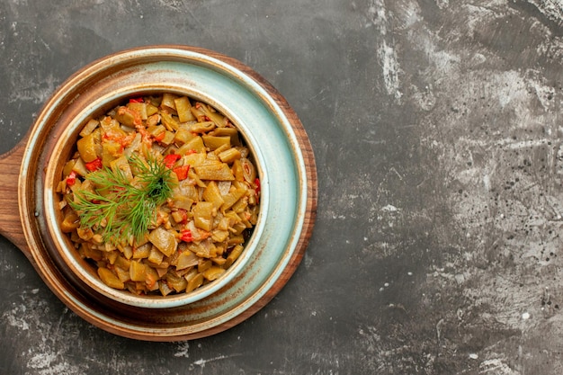 Bovenaanzicht van smakelijke schotel sperziebonen met tomaten op het houten dienblad op de snijplank op de donkere tafel