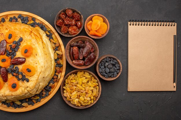 Bovenaanzicht van smakelijke shakh plov gekookte rijst binnen rond deeg met rozijnen op grijze ondergrond