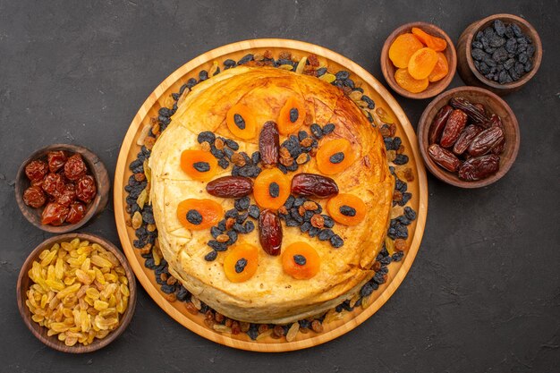 Bovenaanzicht van smakelijke shakh plov gekookte rijst binnen rond deeg met rozijnen op grijze ondergrond