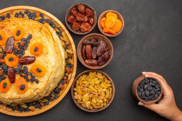 Bovenaanzicht van smakelijke shakh plov gekookte rijst binnen rond deeg met rozijnen op grijze ondergrond