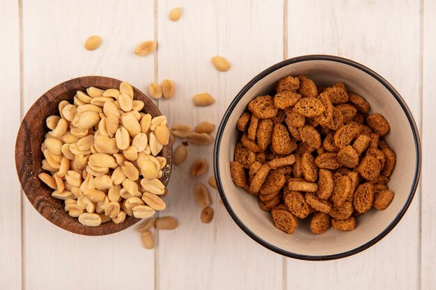 Bovenaanzicht van smakelijke zoute dennenappels op een houten kom met kleine roggebeschuit op een kom op een beige houten tafel