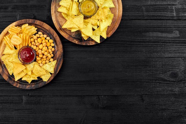 Bovenaanzicht van snacks met saus op zwarte houten tafel.