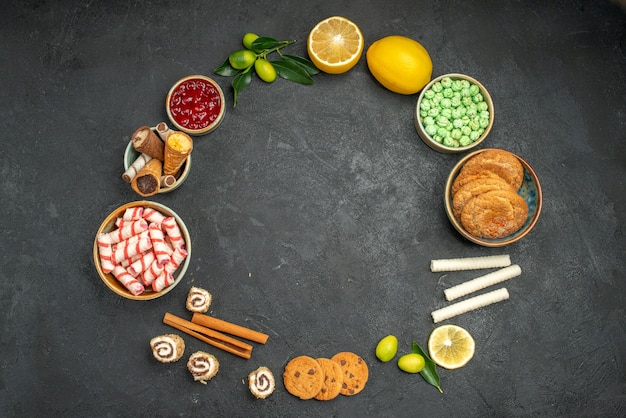 Bovenaanzicht van snoepjes jam citrusvruchten met bladeren snoep koekjes zijn neergelegd in een cirkel