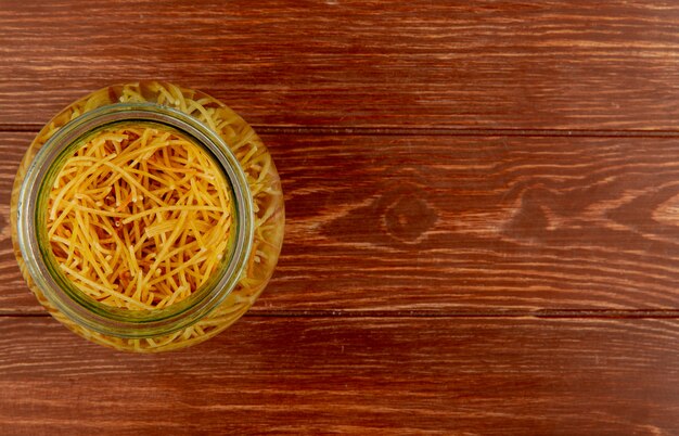 Bovenaanzicht van spaghetti pasta in kom op hout met kopie ruimte