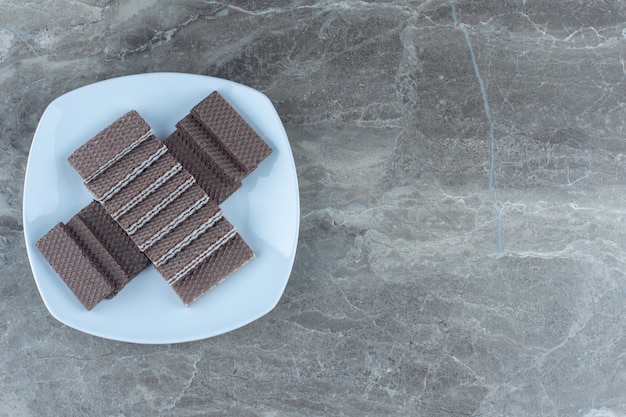 Bovenaanzicht van stapel chocoladewafels op witte plaat.