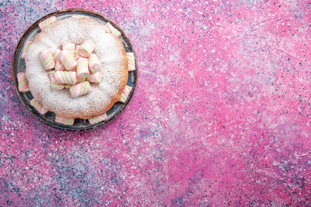 Bovenaanzicht van suiker poedertaart met zoete marshmallows op het roze oppervlak