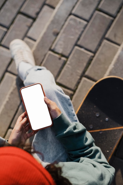 Bovenaanzicht van tiener buitenshuis met behulp van smartphone