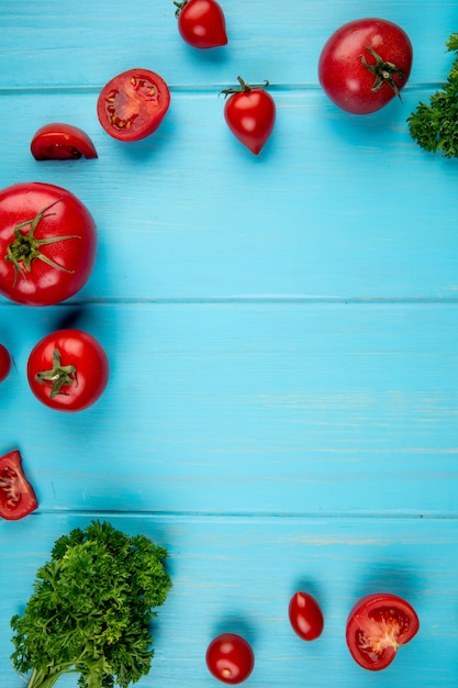 Bovenaanzicht van tomaten en koriander op blauw oppervlak met kopie ruimte