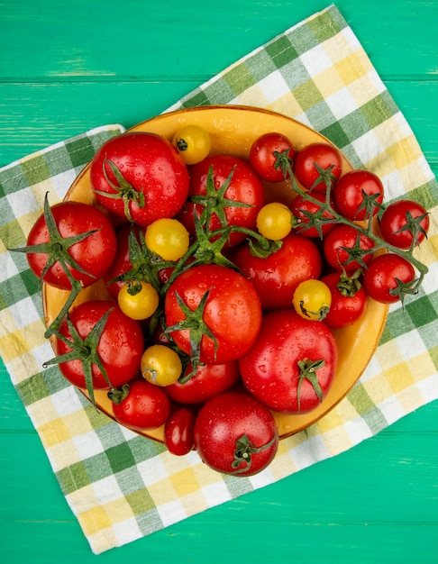 Bovenaanzicht van tomaten in kom op doek op groene ondergrond