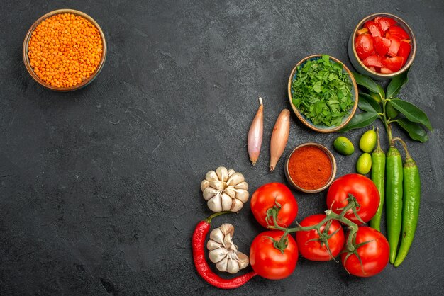 Bovenaanzicht van tomaten, knoflook, ui, hete pepers, tomaten, kruiden, kruiden, kom van linze