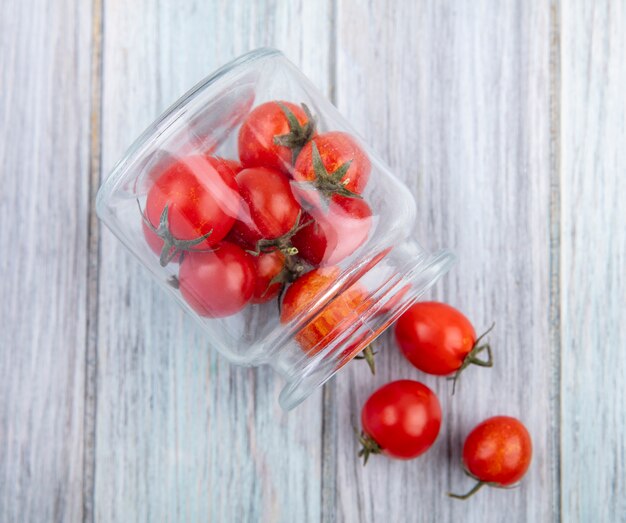 Bovenaanzicht van tomaten morsen uit pot op houten oppervlak