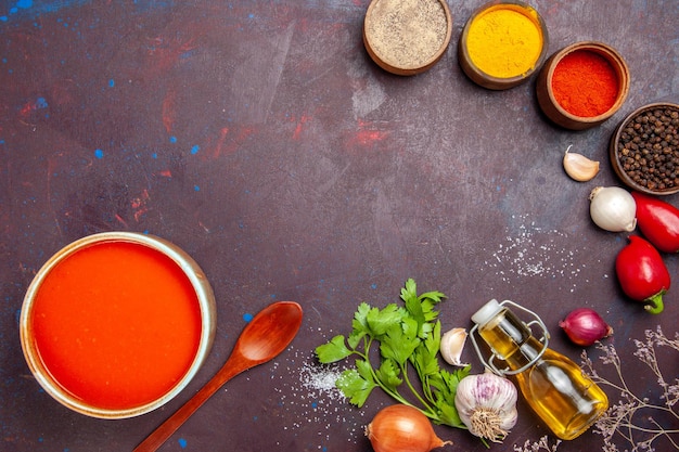 Bovenaanzicht van tomatensoep gekookt van verse tomaten met verschillende smaakmakers op zwart