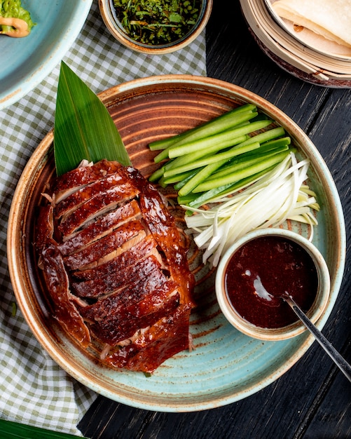 bovenaanzicht van traditionele Aziatische gerechten Pekingeend met komkommers en saus op een bord
