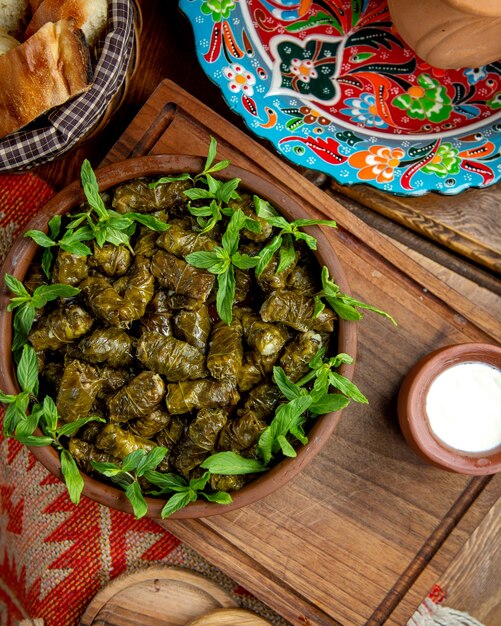 Bovenaanzicht van traditionele dolma in druivenbladeren met zure yoghurt op een houten tafel