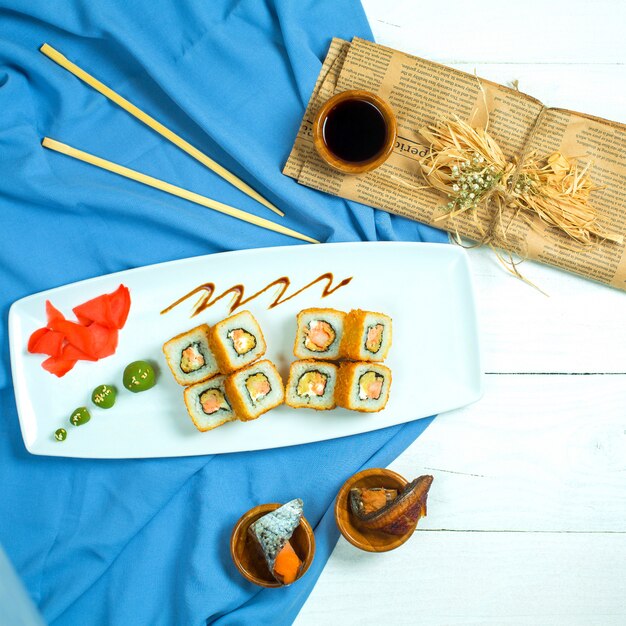 Bovenaanzicht van traditionele Japanse keuken sushi roll met zalm avocado en roomkaas op blauw en wit
