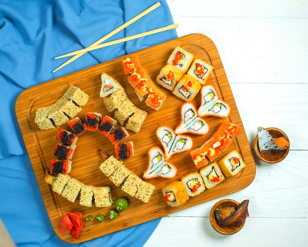 Bovenaanzicht van traditionele Japanse keuken sushi roll met zalm avocado en roomkaas op een houten schotel op blauw en wit