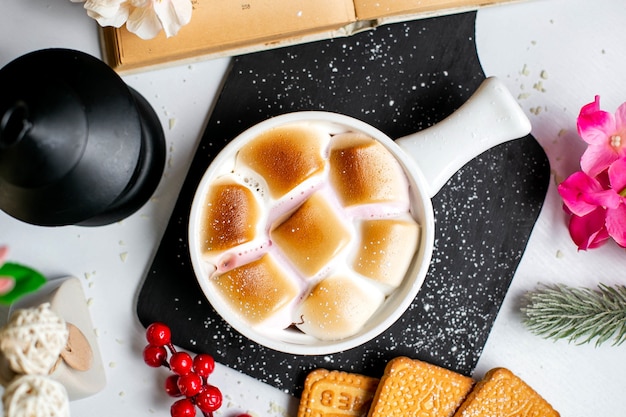 Bovenaanzicht van traditionele zoete aardappel braadpan met marshmallows in geportioneerde vormen op een houten zwarte snijplank