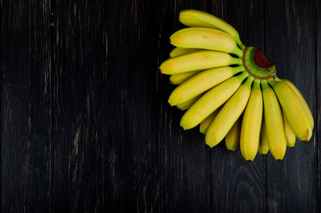 Bovenaanzicht van tros bananen op zwart hout met kopie ruimte