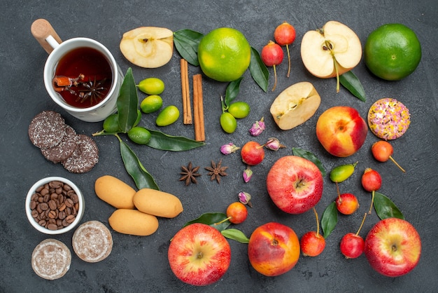 Bovenaanzicht van ver een kopje thee een kopje kruidenthee kaneelstokjes snoep fruit en bessen